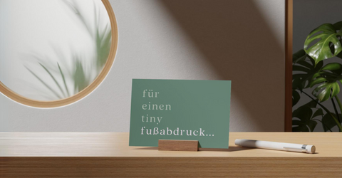 Nachhaltigen Schmuck selber machen: Minimalistische Postkarte in modernen Blau- und Grüntönen, dekoriert mit einer natürlichen Pflanze und dem Schriftzug 'für einen tiny Fußabdruck...' in einem eleganten, minimalistischen Design.
