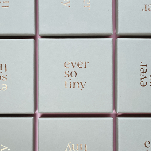 Mintfarbene Schmuckboxen mit goldener Prägung des Logos „ever so tiny“, in einem Raster angeordnet auf rosa Hintergrund. Stilvolle und nachhaltige Verpackung für DIY-Schmucksets.
Elegante Schmuckboxen von „ever so tiny“: Mintfarbene Verpackungen mit goldener Prägung. Nachhaltig produziert in Deutschland – ideal für DIY-Schmucksets und als hochwertige Geschenkverpackung.