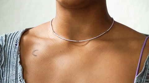 Zarte DIY-Halskette in Lavendel mit goldfarbenen Details und Swarovski-Kristallen. Die minimalistische Kette aus dem ever so tiny Schmuckset wird zu einem grauen, gerippten Oberteil mit lila Akzenten getragen und unterstreicht den filigranen und hochwertigen Stil.