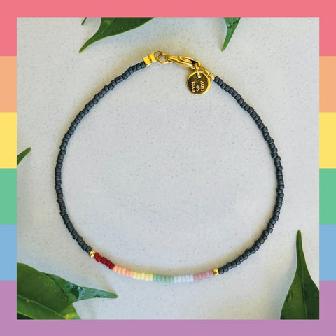 ever so tiny Pride-Edition Armband mit Schwarz-grauen Basisperlen an der Seite und in der Mitte die Regenbogen farbenen Perlen nebeneinandergefädelt. DIY-Schmuckset für Queers und Allys als perfektes Geschenk für andere oder sich selbst.