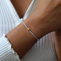 Zartes DIY-Armband in Hellblau mit goldfarbenen Details und Süßwasserperlen, getragen zu einem weißen, gerippten Oberteil mit Reißverschluss. Das Armband aus dem Schmuckset von ever so tiny verbindet minimalistische Eleganz mit nachhaltigem Design.